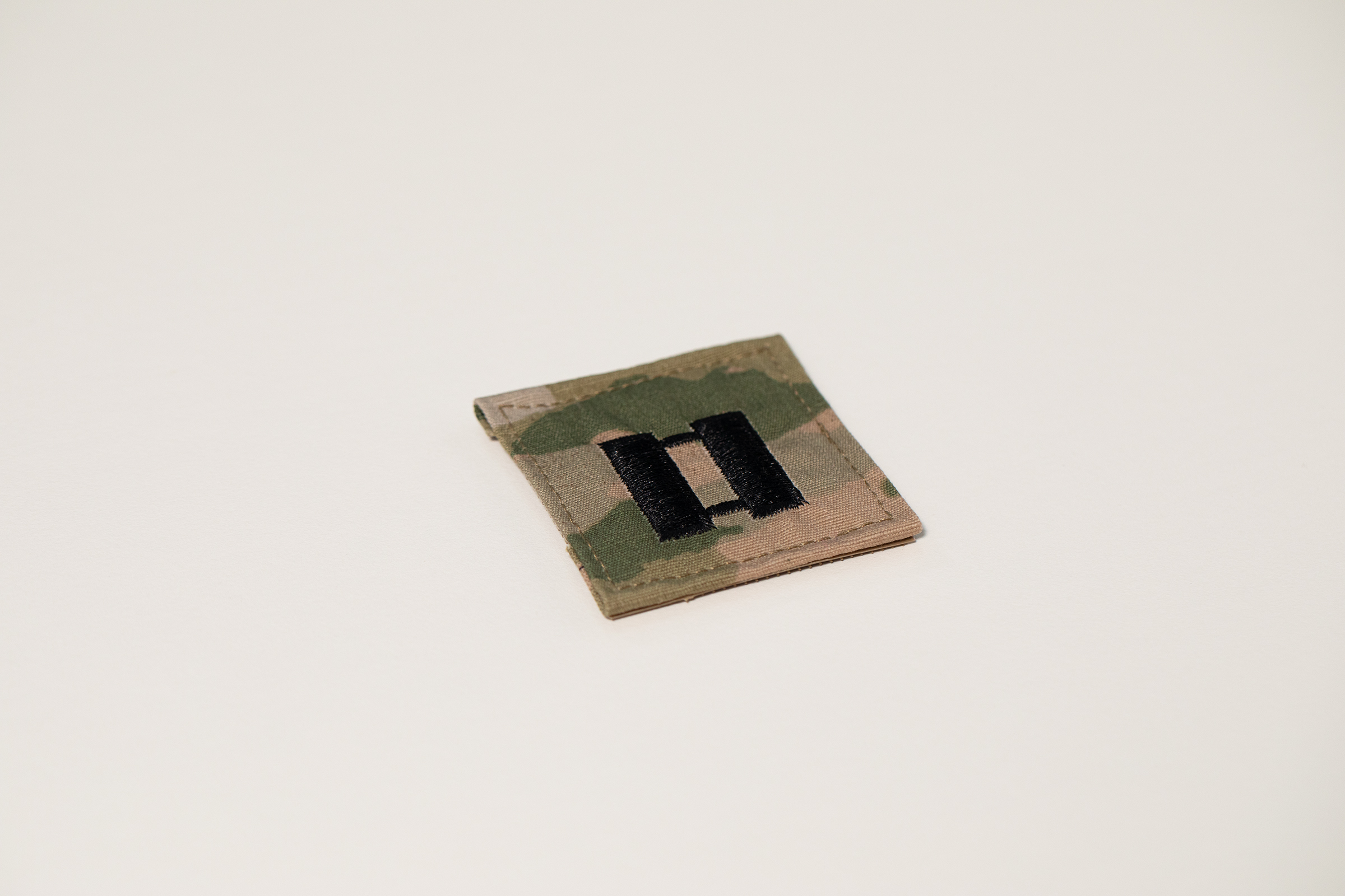 U.S. Army captain’s rank patch photographed on a neutral background, showing the double-bar insignia that inspired the DHC logo.