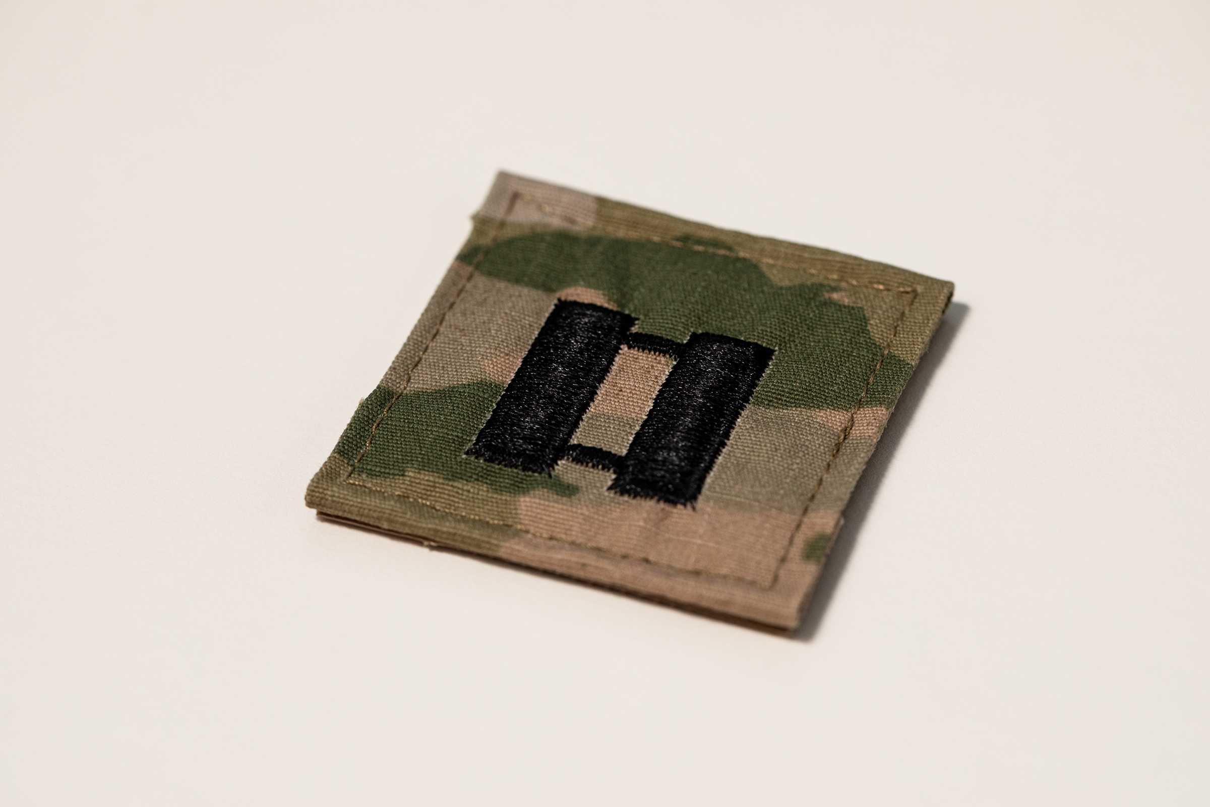 Close-up photograph of a U.S. Army captain’s rank patch showing the embroidered double-bar insignia.